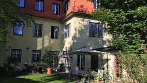 A two-story building with a yellow facade, multiple windows, and a covered outdoor seating area with potted plants. - Beautiful living near Schönbrunn (Wien)
