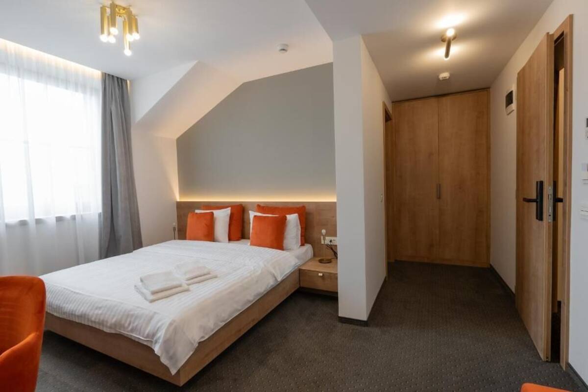 Ein modernes Hotelzimmer mit einem großen Bett, einem Holzschrank und einem Nachttisch.
