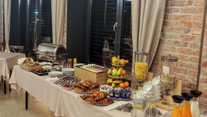 Un buffet proposant une variété de plats et de boissons, un mur en briques et une fenêtre avec des rideaux.