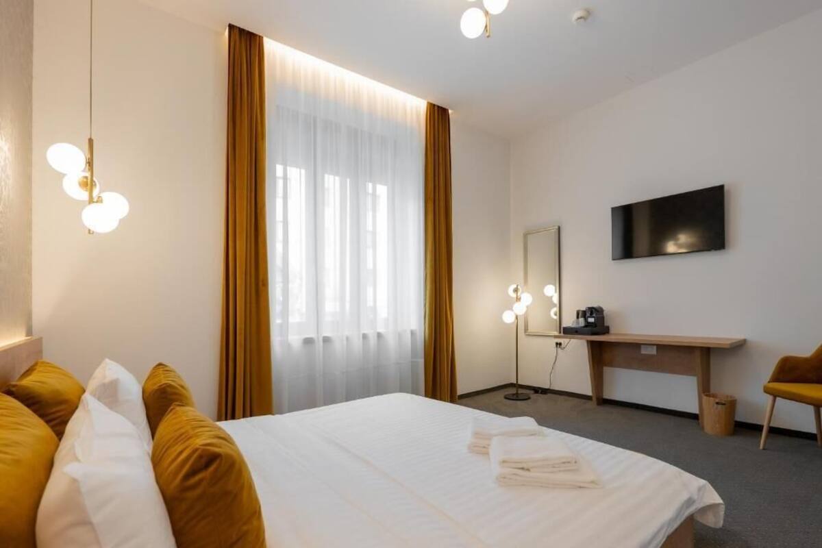 Ein Hotelzimmer mit einem Bett, einem Frisiertisch mit Beleuchtung, einem Schreibtisch und einem Fernseher.