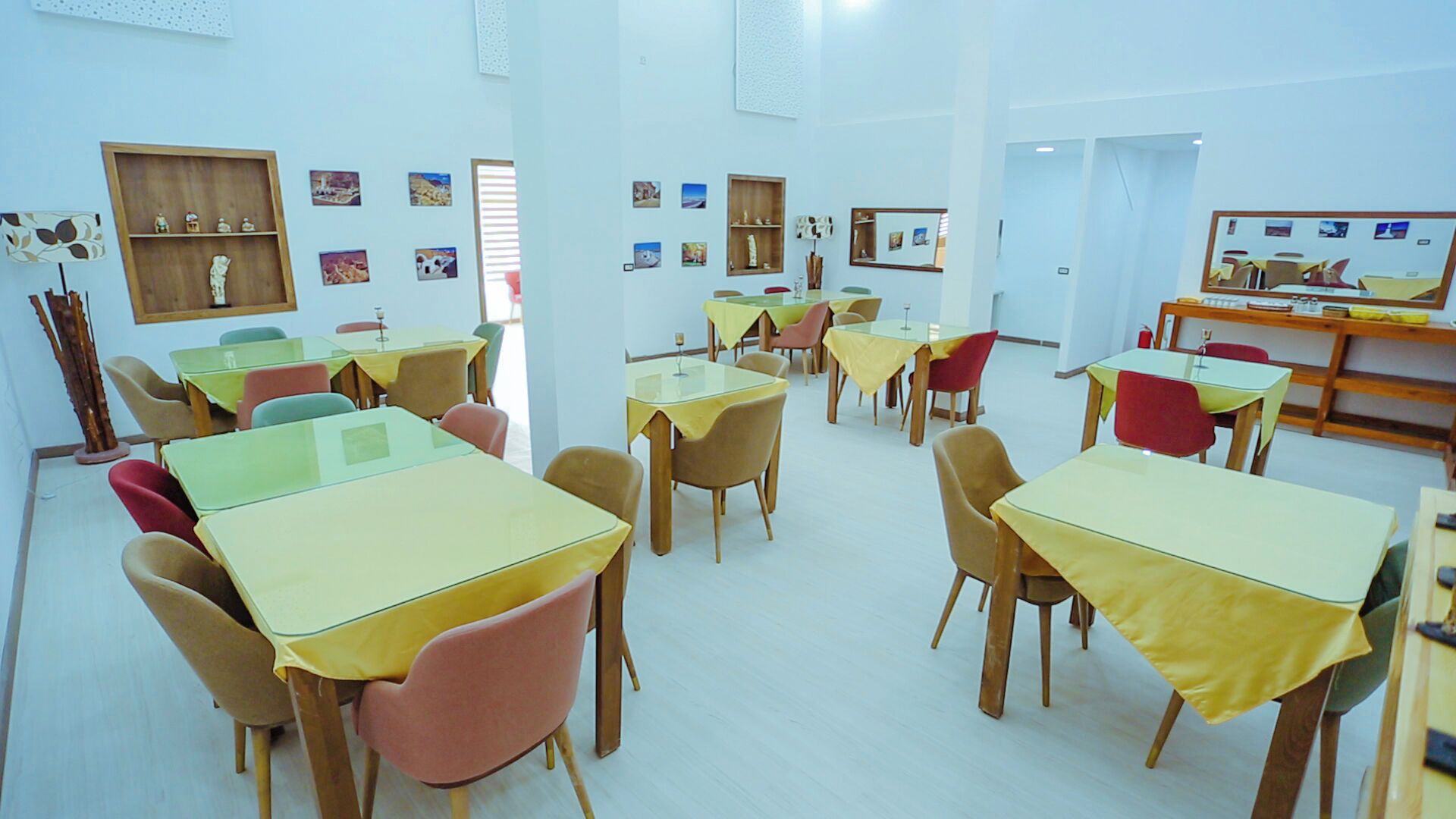 A classroom with tables and chairs, educational posters on the walls, and a television screen.