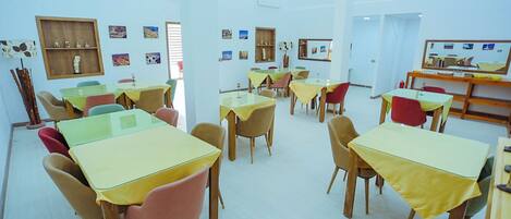 A classroom with tables and chairs, educational posters on the walls, and a television screen.