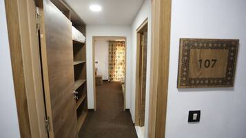 Un pasillo estrecho con puertas de madera, piso cubierto de alfombra y una cortina estampada al final. Una placa de madera con el número 107 está colocada en la pared.