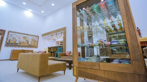 A modern interior with a glass display case filled with decorative items, a beige sofa, and a wooden cabinet. - Ecolodge Ksar Ghilane (Douz Sud)