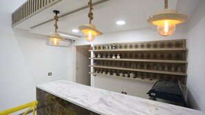A reception area with a marble counter, hanging rope lights, and shelves with glassware. - Ecolodge Ksar Ghilane (Douz Sud)
