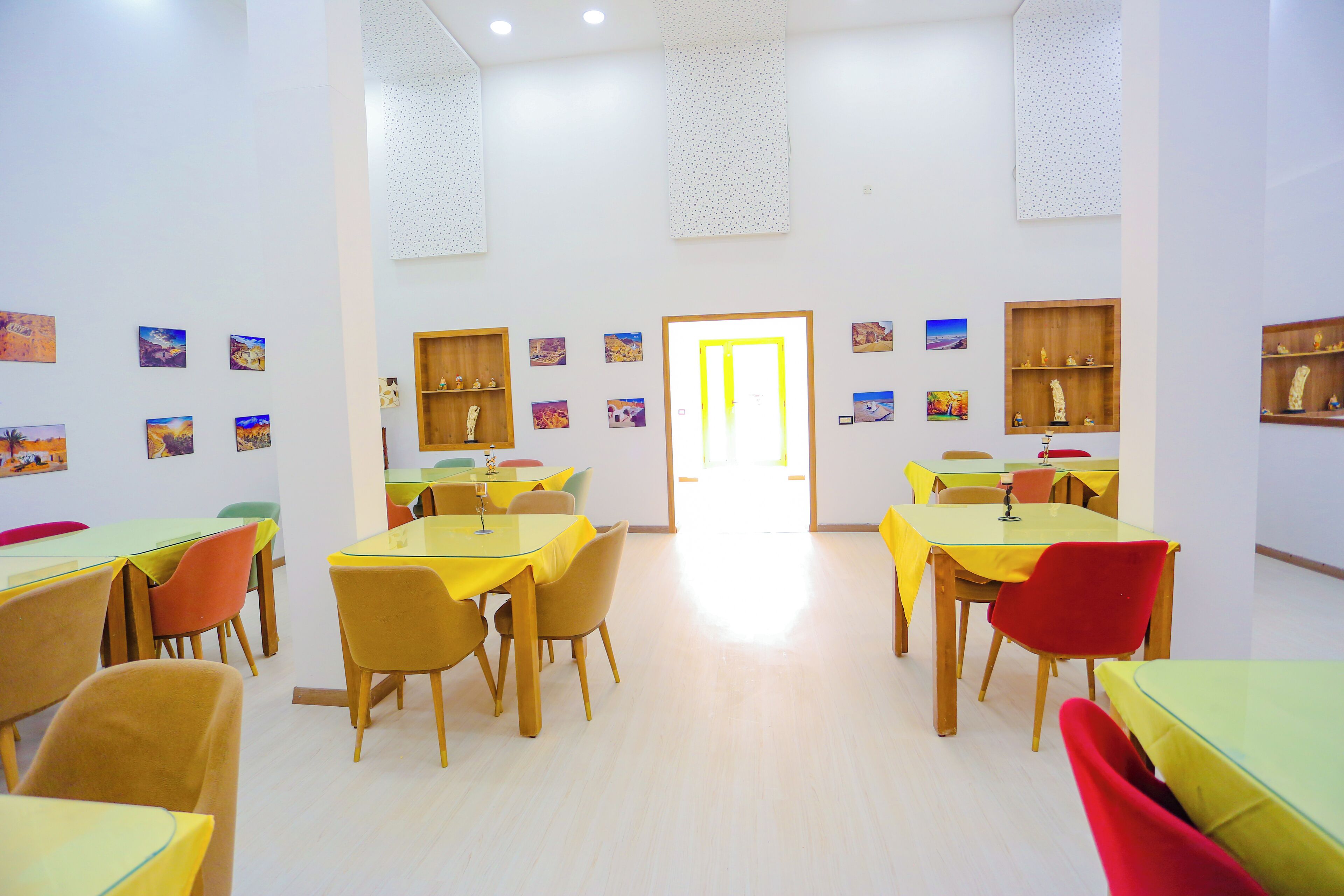 A dining area with multiple tables and chairs, a bright interior, and artwork on the walls.