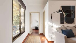 Ein modernes Wohnzimmer mit großem Fenster, einer Couch, einem Teppich und einer Stehlampe.