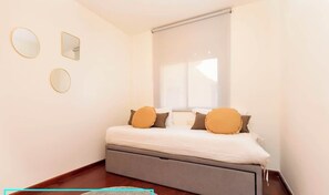 Quarto com uma cama, janela com persianas e três espelhos fixados na parede.