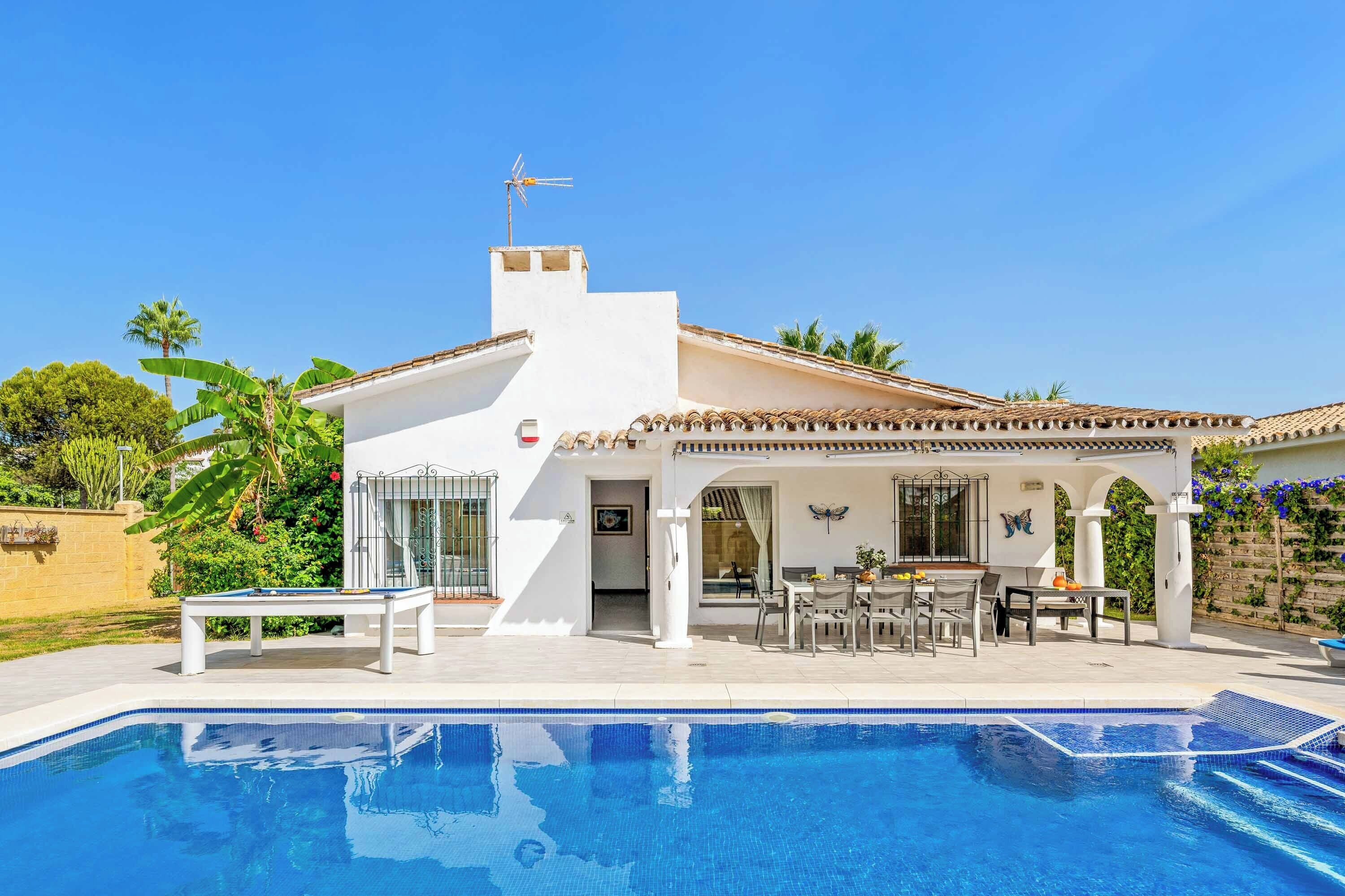 A modern house with a swimming pool, a patio with outdoor furniture, and a view of the surrounding greenery.