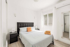 Ein Schlafzimmer mit Bett, Nachttischen, einem Spiegel und einem Fenster.