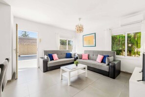 A modern living room with a grey sofa, white coffee table, and a ceiling light fixture. - Villa Esmerelda Sun - Four Bedroom Villa, Sleeps 8 (Bel-Air)