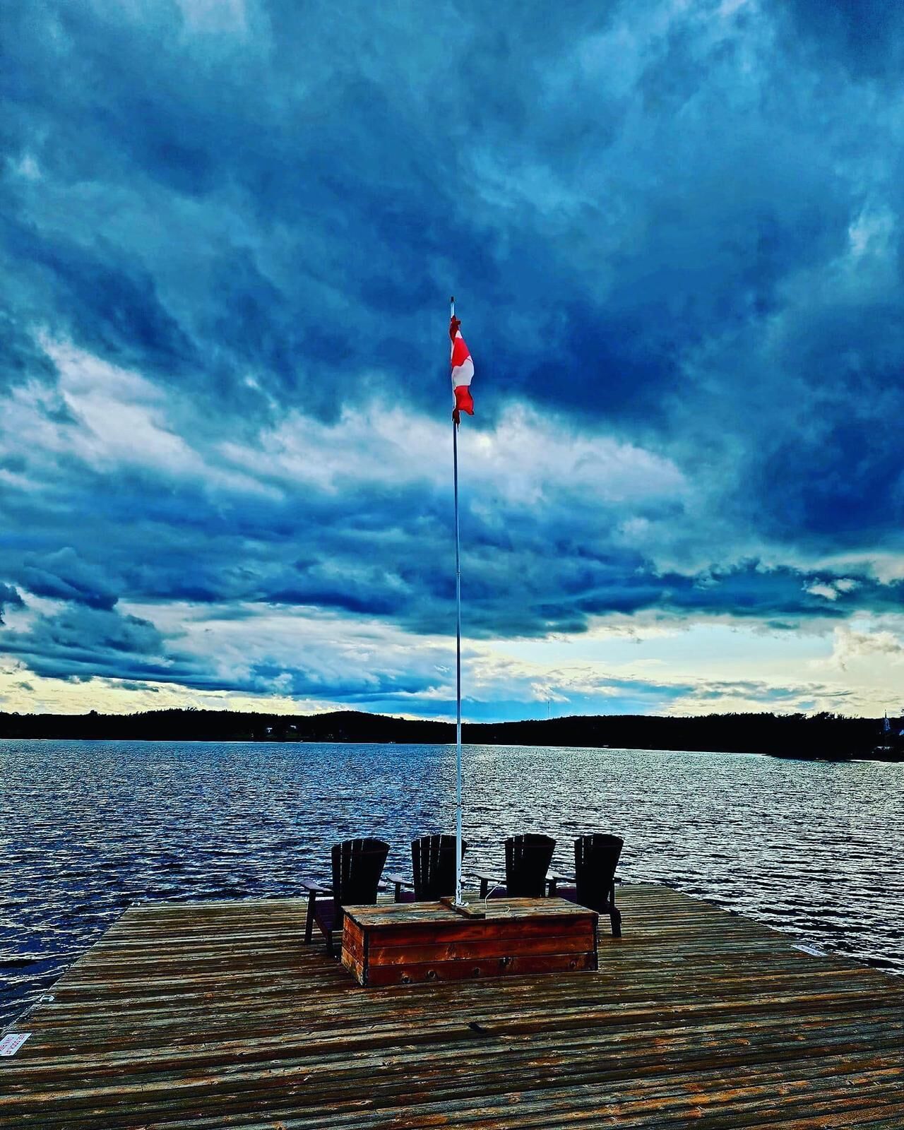 A wooden dock with a flagpole and a bench.