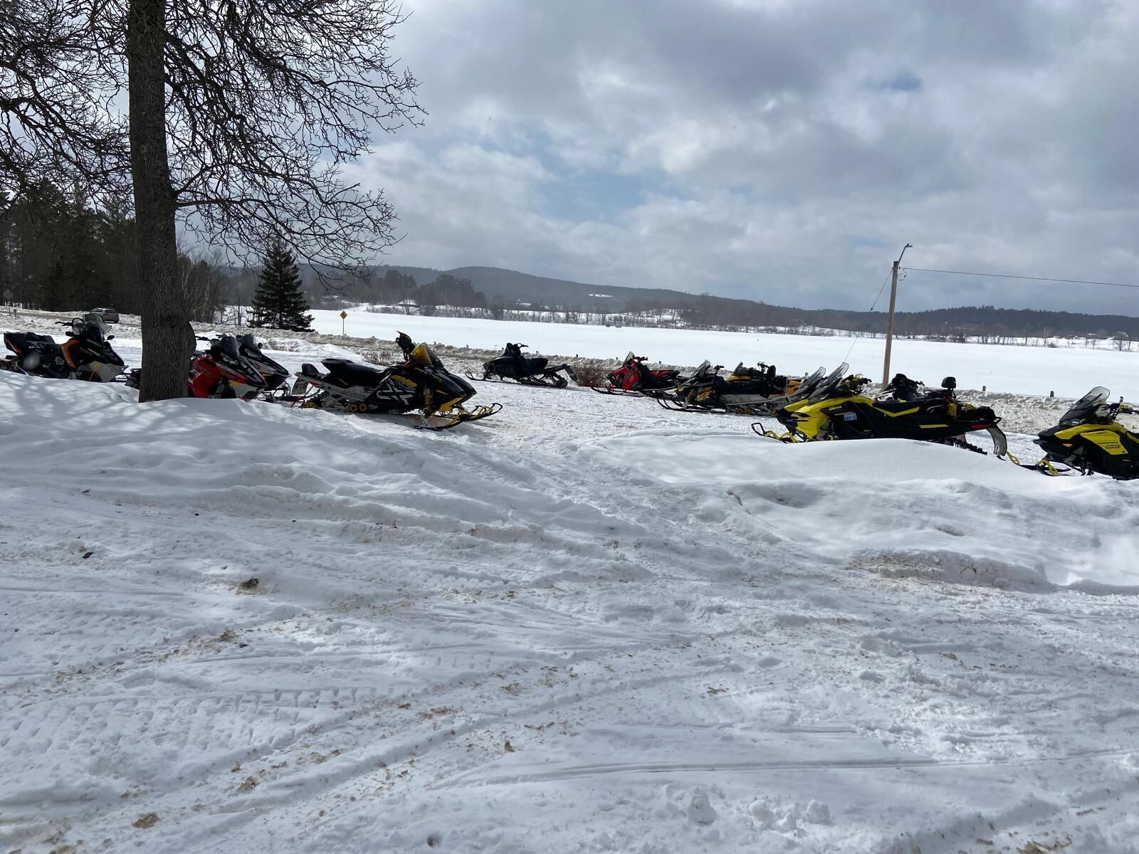 Una fila de motos de nieve estacionadas en una pendiente nevada bajo un cielo despejado.