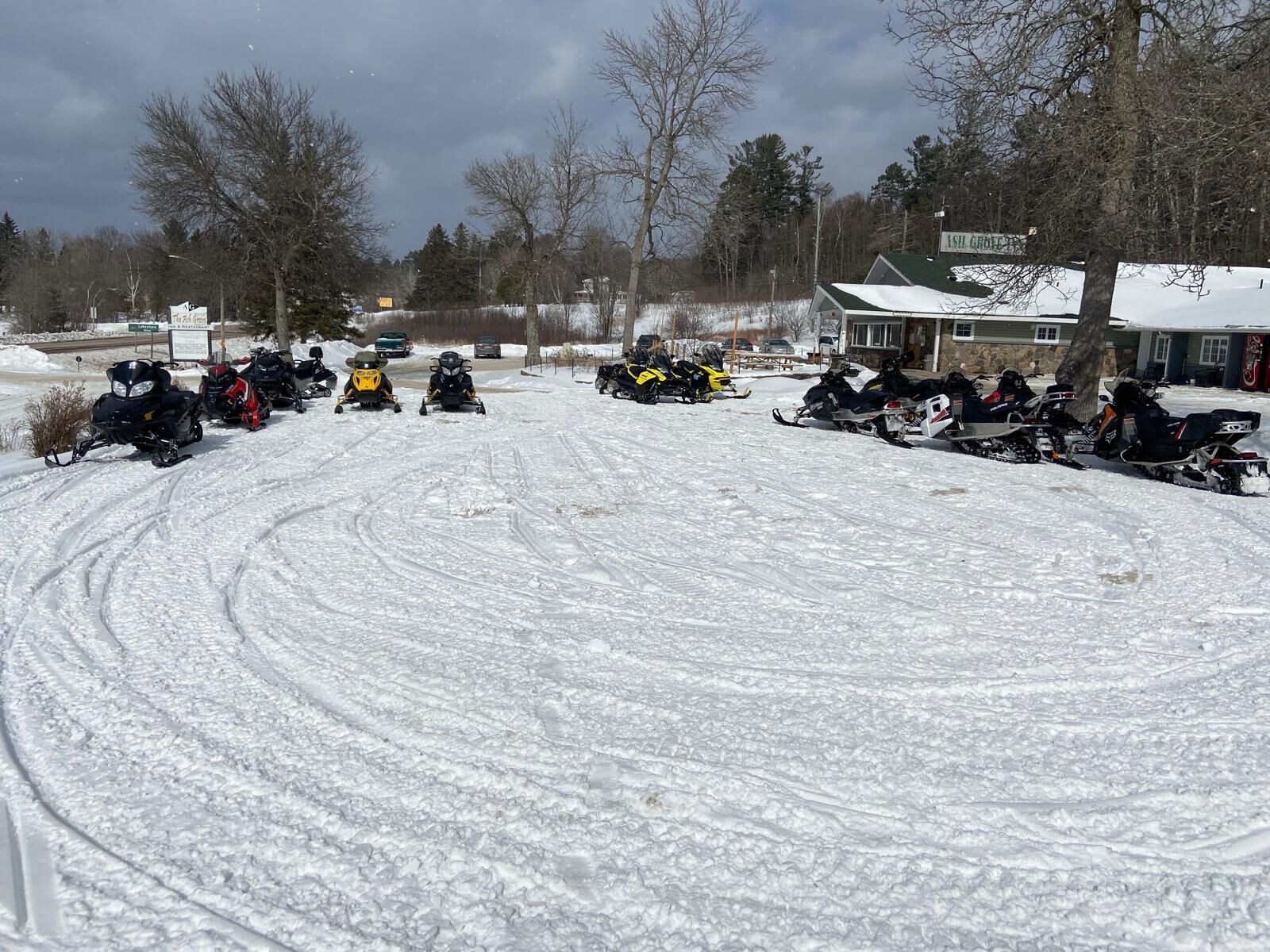 Un estacionamiento cubierto de nieve con varias motos de nieve estacionadas en filas.