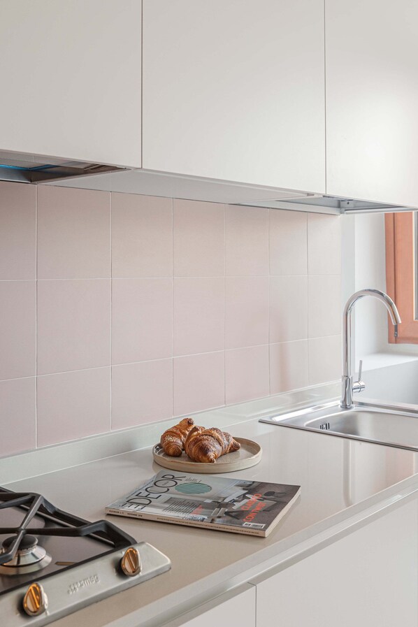 A modern kitchen with a gas stove, a sink, and a magazine on the counter.