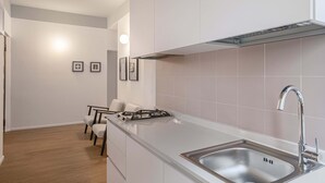Une cuisine moderne dotée d’un évier en acier inoxydable, d’une cuisinière à gaz et de meubles de rangement blancs.