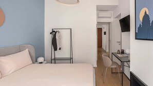 Een slaapkamer met een bed, een bureau, een stoel, een kledingkast en een televisie aan de muur.
