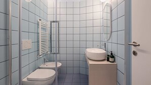 Een compacte badkamer met toilet, wastafel en een douchecabine van glas.