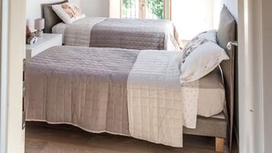 A bedroom with a sloped ceiling, skylight, two beds, and a nightstand with a lamp.