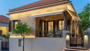 A modern house with a balcony, a small tree, and a staircase leading to the entrance.