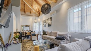 A modern living room with a high ceiling, a glass coffee table, a sofa, and a dining area with chairs and a table.