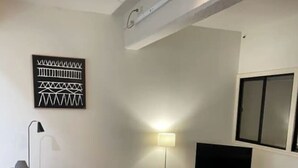 Una sala de estar moderna con un sofá seccional gris, una lámpara de pie, un televisor sobre un mueble de madera y un televisor montado en la pared.