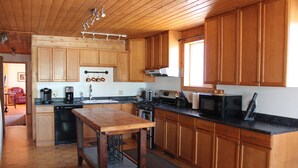 A kitchen with wooden cabinets, a wooden table, and various appliances like a microwave and coffee maker.