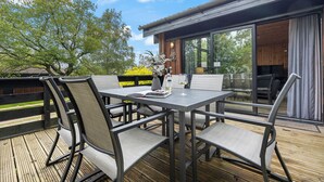 An outdoor dining area with a table and chairs, a vase with flowers, and a bottle of wine. - Newsham Lodge (Penrith)