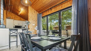 A dining area with a wooden table set for four, surrounded by chairs with cushioned seats. - Newsham Lodge (Penrith)