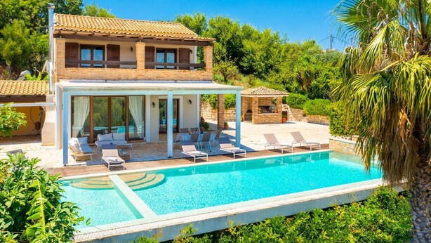 Une maison à deux étages dotée d’une piscine, d’un espace extérieur aménagé et d’un coin barbecue en pierre.