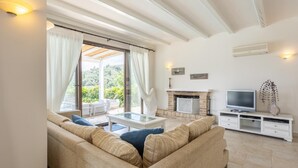 Un salon spacieux comprenant un canapé, une table basse en verre, une cheminée et un téléviseur.