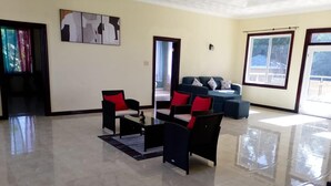 A spacious living room with a large window, a sofa set, and a coffee table. - La Costa Villa (Montego Bay)