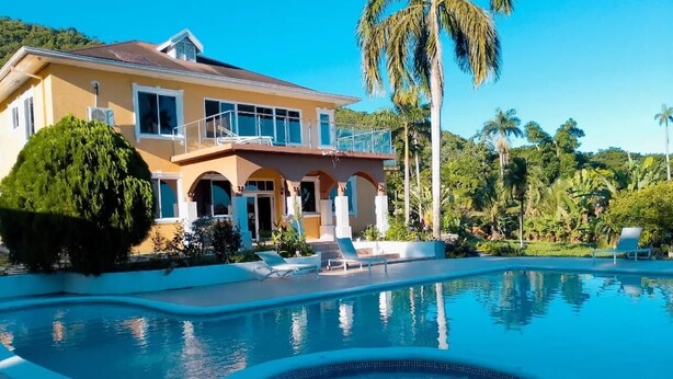 A large house with a swimming pool, surrounded by lush greenery and palm trees. - La Costa Villa (Montego Bay)