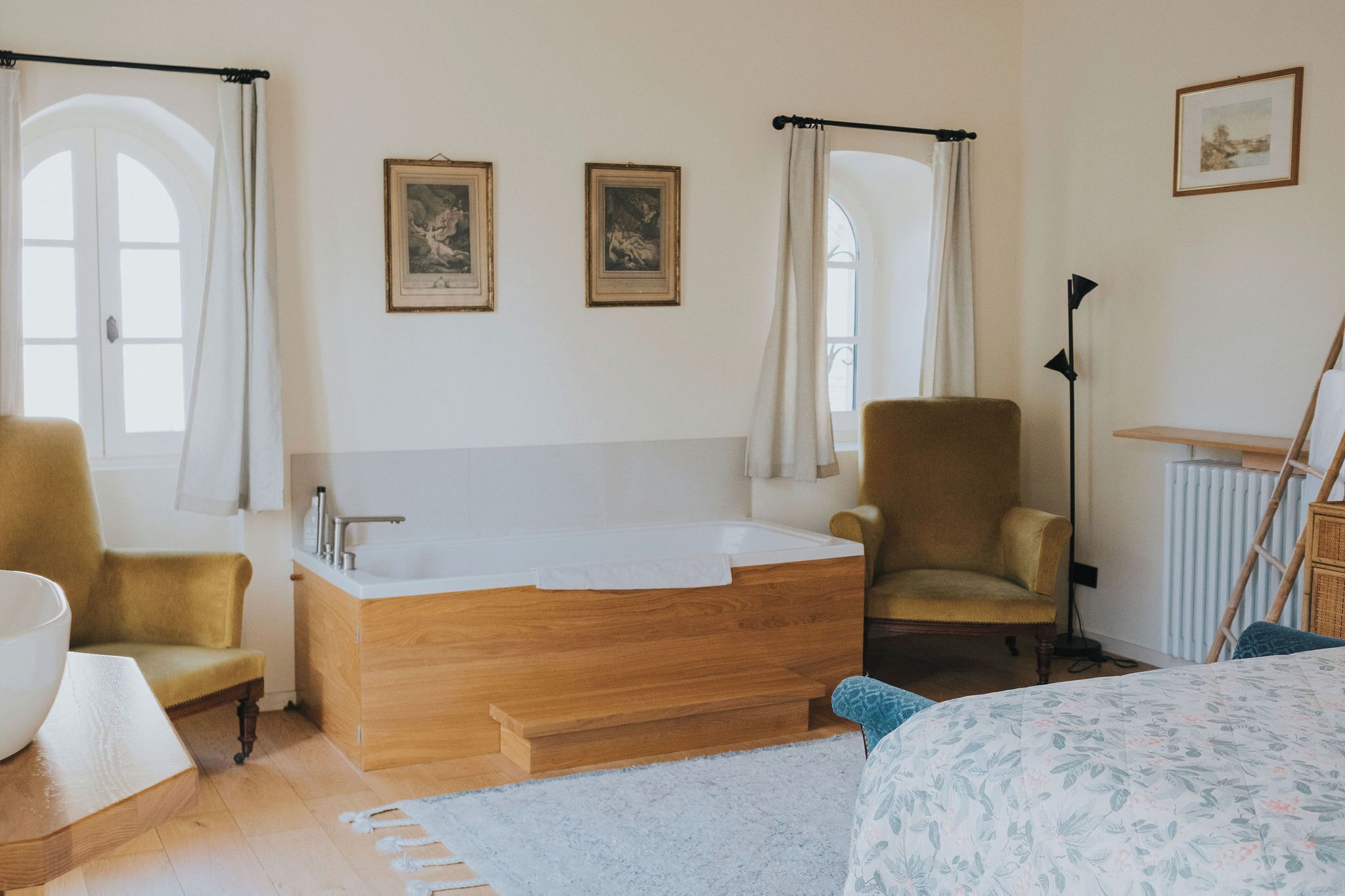 Un baño moderno con una bañera independiente, tocador de madera y dos sillones.