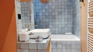 Ein Badezimmer mit einer weißen Badewanne, einem Waschbecken mit Spiegel und einer gefliesten Duschkabine.