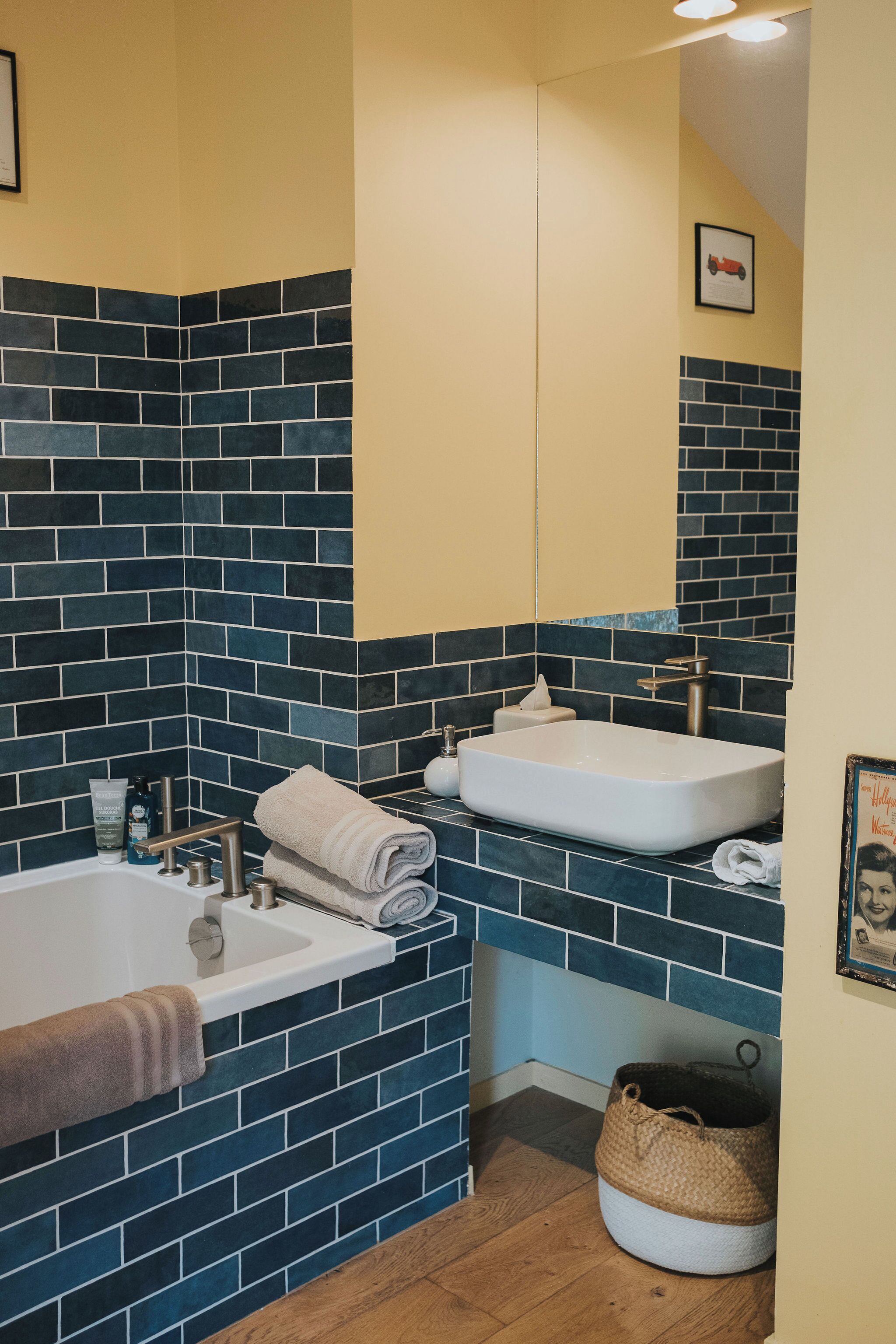 A bathroom with a bathtub, a sink, and a mirror. There are towels and toiletries on the counter.