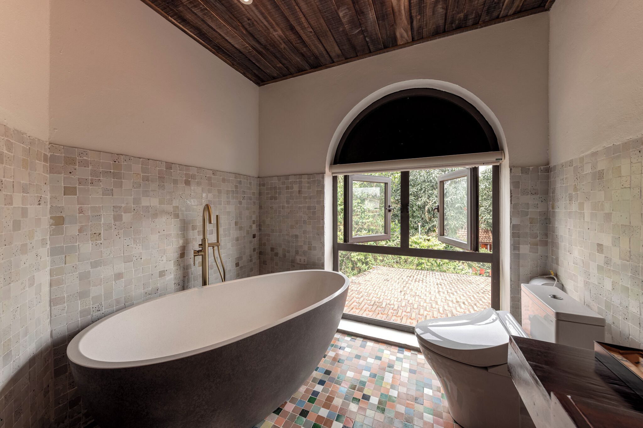 A modern bathroom with a freestanding bathtub, a toilet, and a sink.