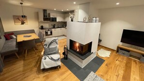A modern living room with a fireplace, a dining area, and a kitchen. - Chalet in Alps Near Ski Lift & Slope (St. Ulrich Am Pillersee)