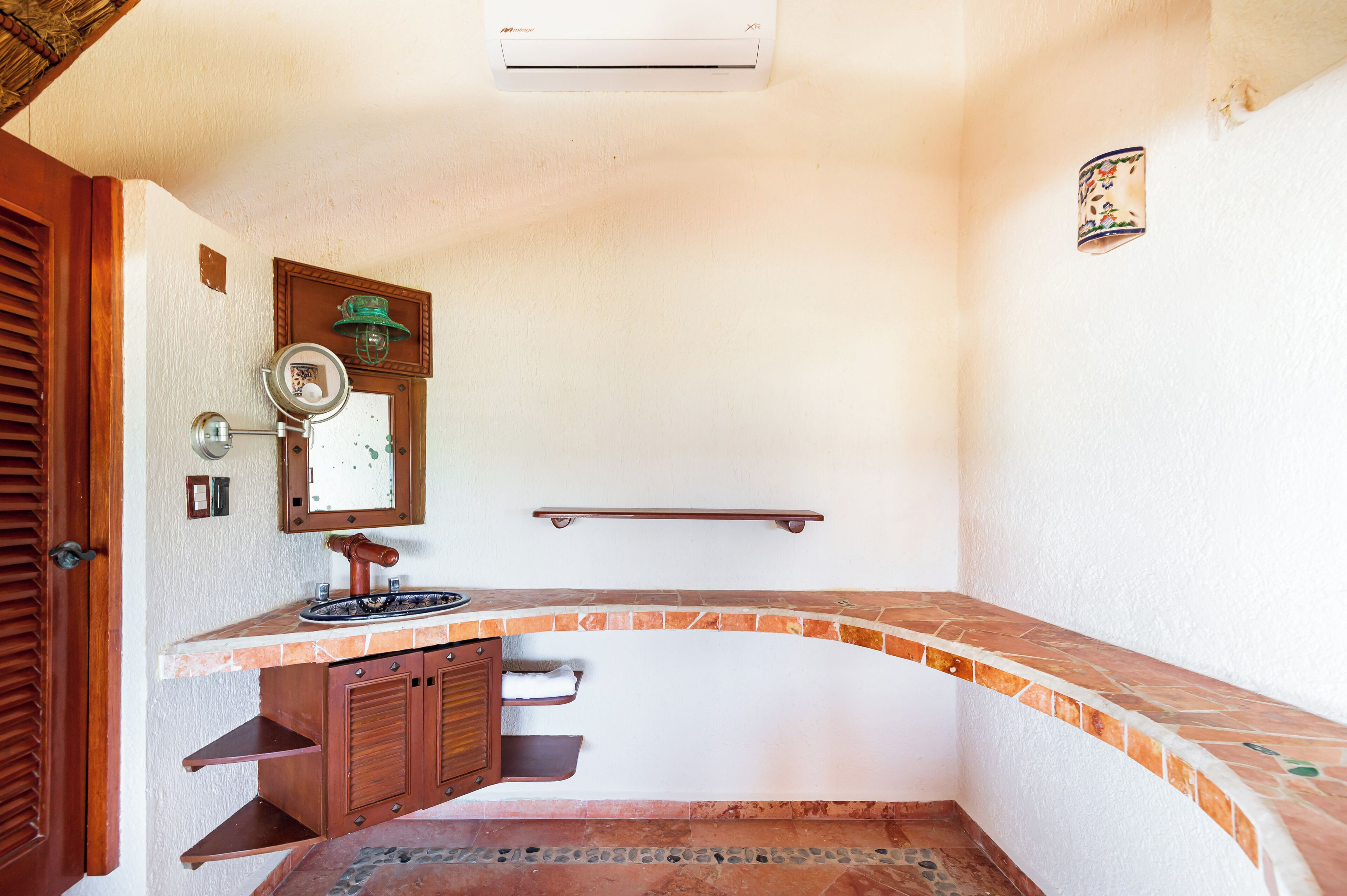 A bathroom with a curved tile countertop, a wooden cabinet, a mirror, and a towel rack.