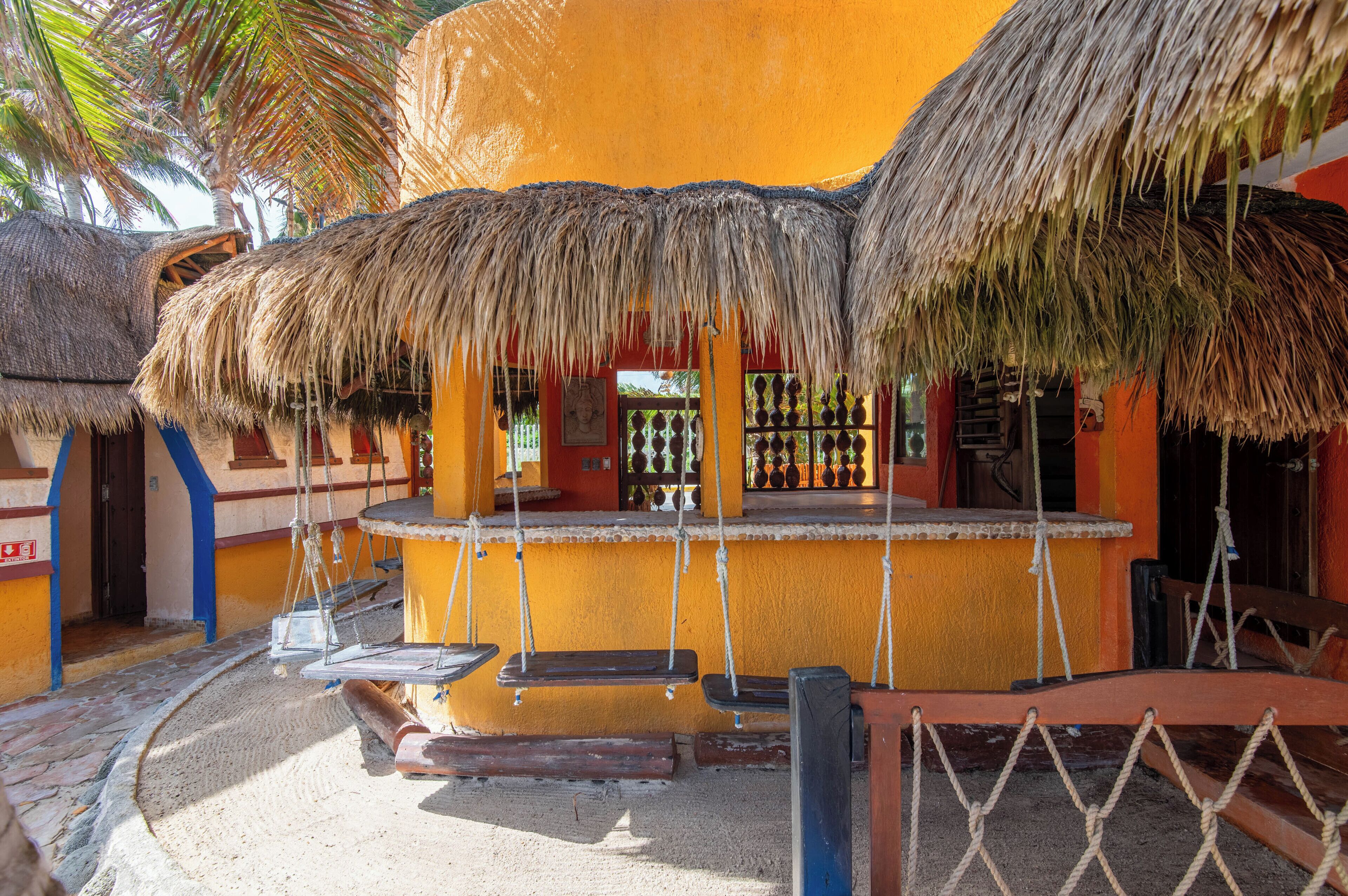 A thatched-roof structure with a swing set and a small pool area.