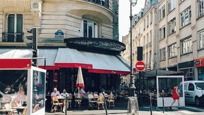 Ein Café mit Außenbereich, einem überdachten Eingang und einer Fußgängerquerung.