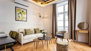 Ein modernes Wohnzimmer mit Sofa, Couchtisch, Sessel und rundem Tisch mit Spiegel.