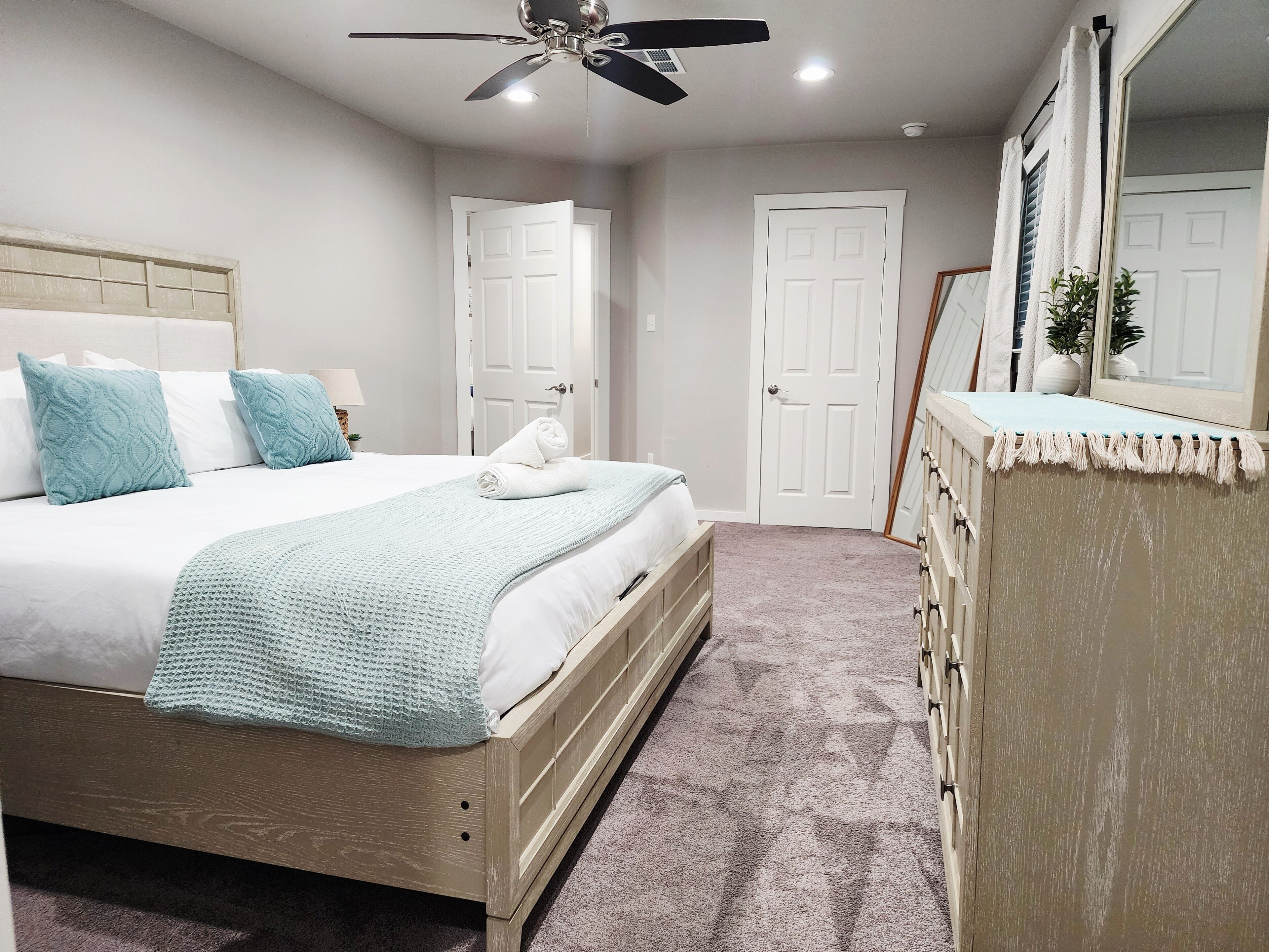 Un dormitorio con cama, ventilador de techo, cómoda y espejo.
