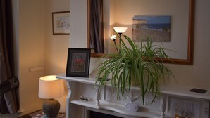 A room with a fireplace, a framed picture, a lamp, and a potted plant. - Tilling View  (Rye)