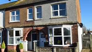 A two-story house with a brick facade, white-framed windows, and a small front garden with potted plants. - Tilling View  (Rye)