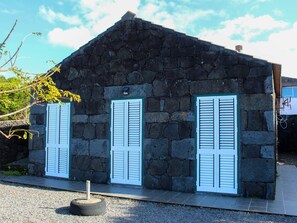 A stone building with three white shutters and a small door. - Atlantis Breeze (Madalena)