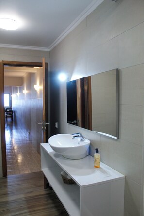 A modern bathroom with a large mirror, white sink, and a bottle of hand soap. - Atlantis Breeze (Madalena)