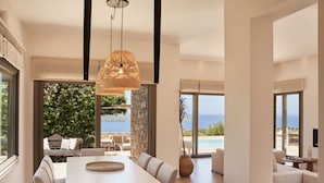 Un interior modern amb zona de menjador, vistes al mar i una piscina.
