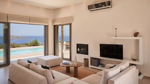 Un saló modern amb un televisor gran, seients confortables i vista al mar.