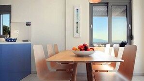 Un'area pranzo moderna con un tavolo e sedie in legno, una ciotola di frutta e una vista dalla finestra.